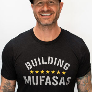 Black Building Mufasas t shirt with white text and gold star details worn from front view
