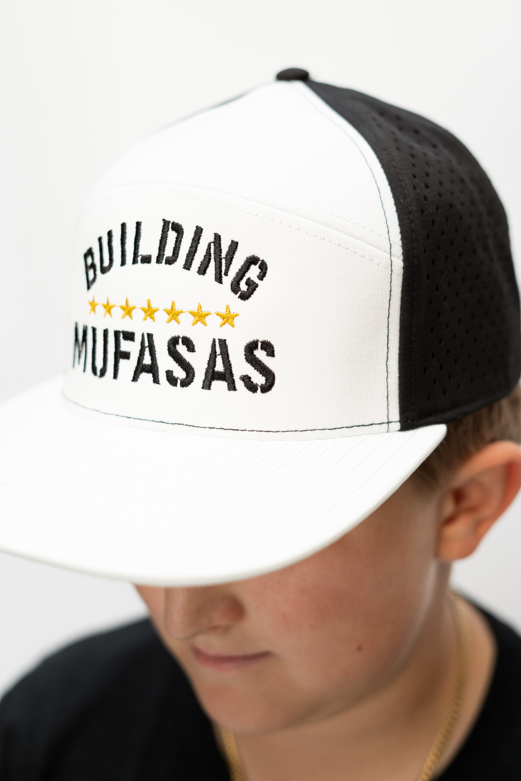 White and black Building Mufasas embroidered hat with gold star details worn from side angle